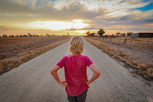 Boy walking along country road at sunset - Australian Stock Image