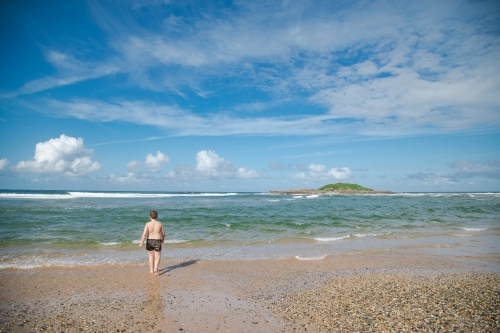 Boy walking towards the water on the beach at Coffs Harbour - Australian Stock Image