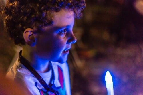 Boy with candle at Christmas carols in the park at night time - Australian Stock Image