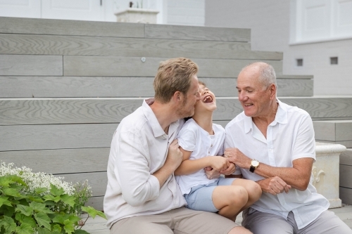 Boy with father and grandfather sitting on outdoor stairs - Australian Stock Image
