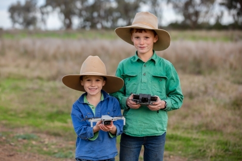 Boys using a drone in the paddock on a farm - Australian Stock Image