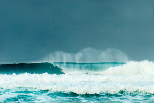 Breaking ocean wave with mist blowing back under stormy skies - Australian Stock Image