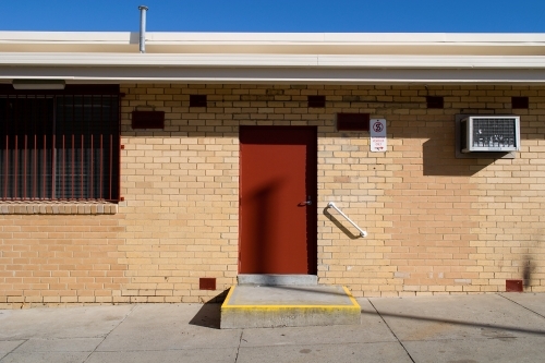 Brick building with a red door, yellow entry and under a blue sky