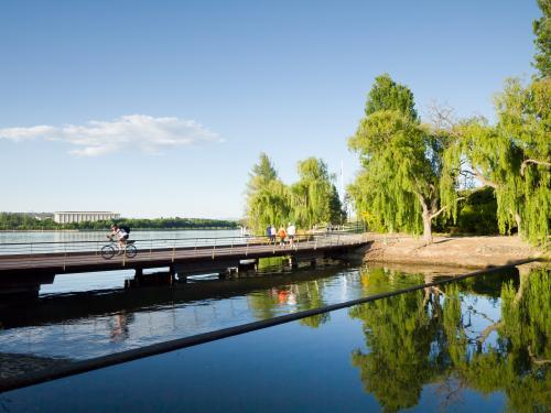Bridge across water with cyclist and people - Australian Stock Image
