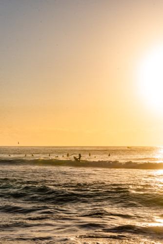 Bright Sun Glare Over Ocean and Beach with surfers - Australian Stock Image