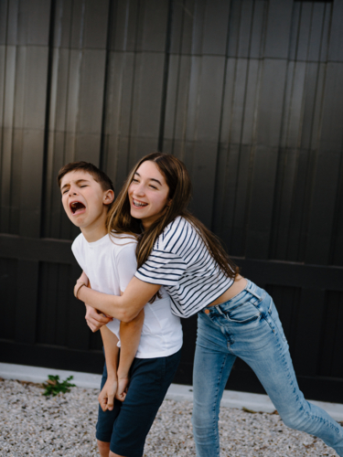 Brother and sister goofing around outside their home - Australian Stock Image