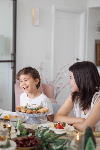 Brother and sister laughing at table together - Australian Stock Image
