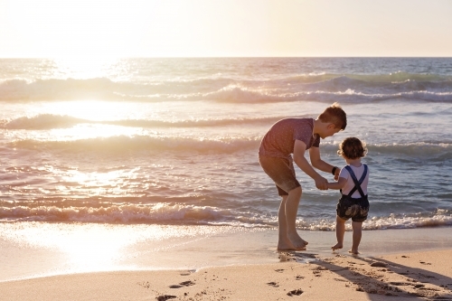 Brother and Sister Playing On The Beach At Sunset At The Water's Edge - Australian Stock Image