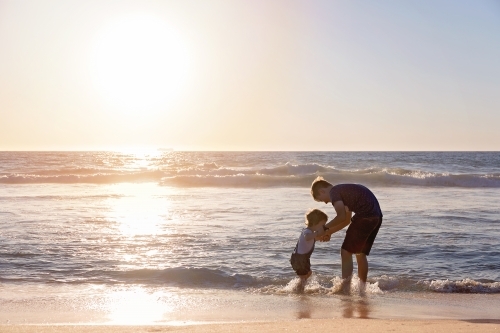 Brother and Sister Playing On The Beach At Sunset Paddling In The Water - Australian Stock Image