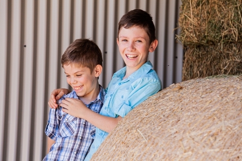 Brothers playing together in hay shed - Australian Stock Image