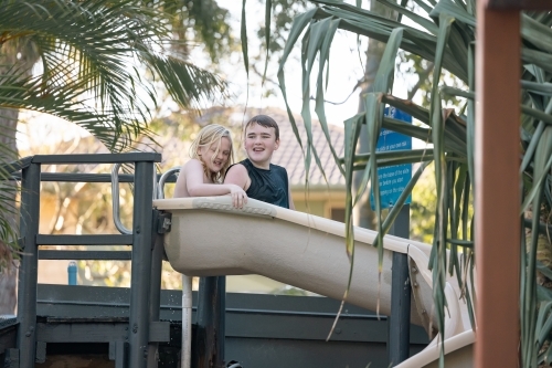 Brothers riding water slide together on holiday at caravan park - Australian Stock Image
