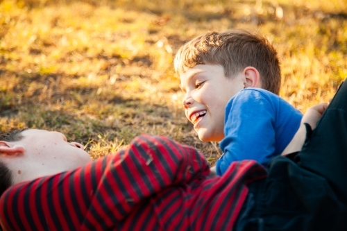 Brothers tackle wrestling each other outside - Australian Stock Image