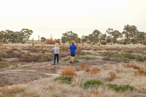 Brothers walking together exploring desolate dry lake. Family outing in the Australian bush. - Australian Stock Image