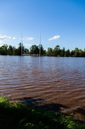Brown floodwaters covering park playing field after river broke banks - Australian Stock Image