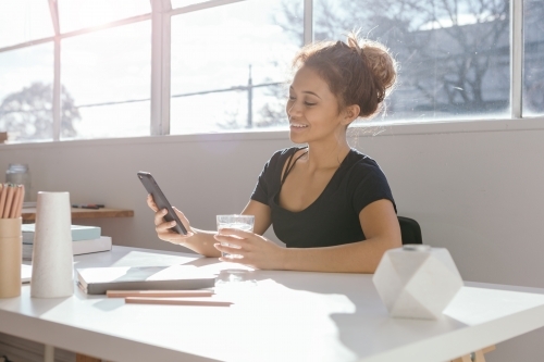 Brunette woman surfing the internet on her mobile device in an office - Australian Stock Image