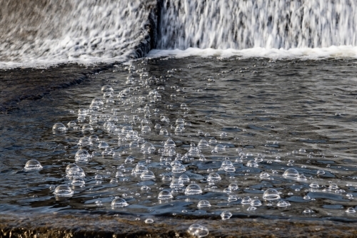 Bubbles in water spilling from dam wall