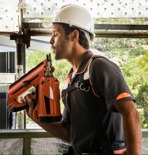 Builder on residential building site holding nail gun like a smoking gun