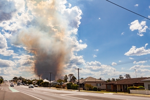 Bushfire smoke billowing into sky behind houses along main street of country town in Hunter Valley - Australian Stock Image