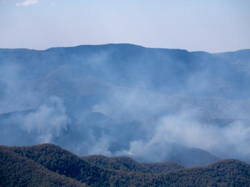 Bushfire smoke in rugged timbered country - Australian Stock Image