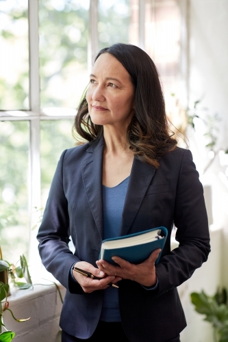 Business woman standing in studio holding a folder - Australian Stock Image