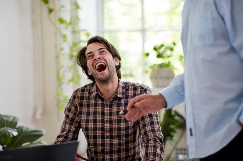 Businessman laughing in an open space office - Australian Stock Image