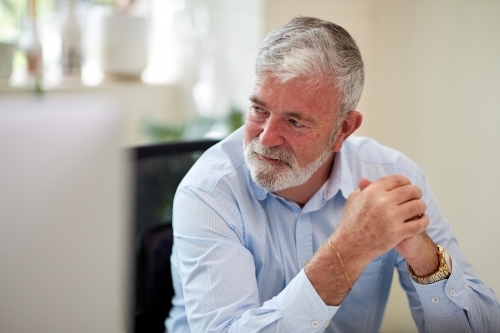 Businessman sitting at a desk in an open office studio - Australian Stock Image