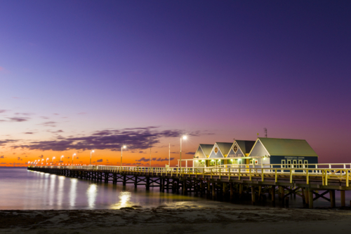 Busselton Jetty illuminated at dusk with vibrant purple and orange sky. - Australian Stock Image