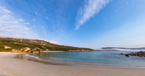 calm water in a peaceful little cove with cloud-swept blue sky - Australian Stock Image