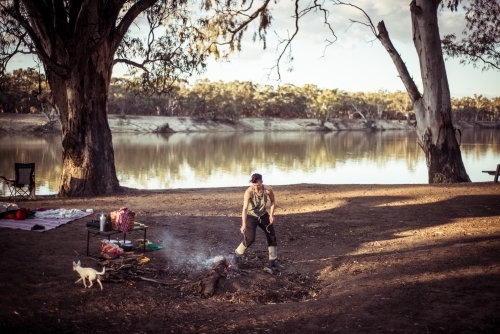Camping life - woman by the campfire the river - Australian Stock Image