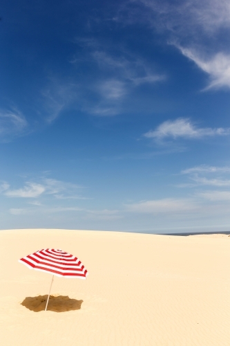 Candy stripe beach umbrella on a sand dune - Australian Stock Image
