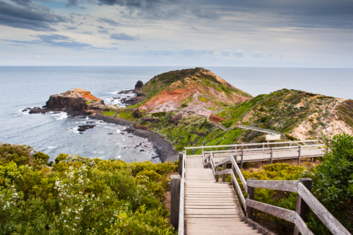 Cape Schanck boardwalk runs towards the sea and rock formation known as London Bridge - Australian Stock Image