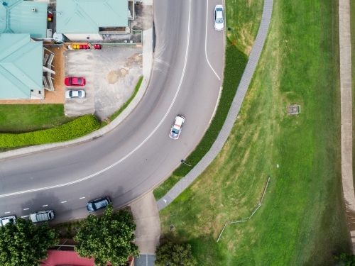 Car driving on curved corner bend in road in town from above - Australian Stock Image