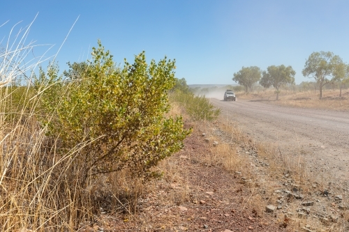 car in distance driving down dusty unsealed road - Australian Stock Image