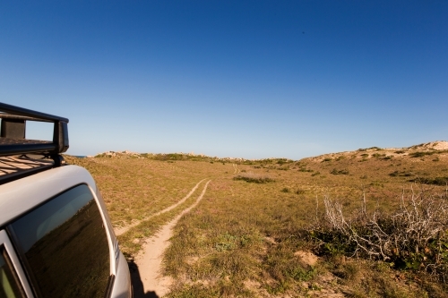 Car on four wheel drive trail in sand dunes under blue sky - Australian Stock Image