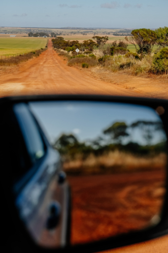 Car side mirror reflection and red dirt road - Australian Stock Image