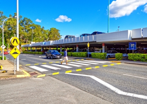 Car stopping at pedestrian crossing waiting for a man walking across the street - Australian Stock Image