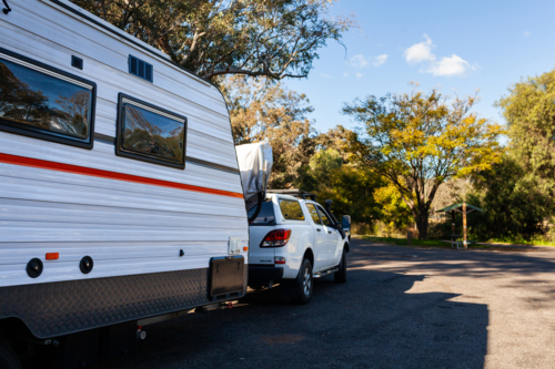 car towing caravan stopped at roadside rest area in bushland - Australian Stock Image