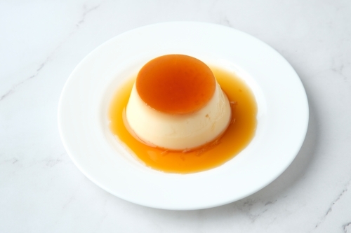 Caramel pudding plate on marble surface - Australian Stock Image