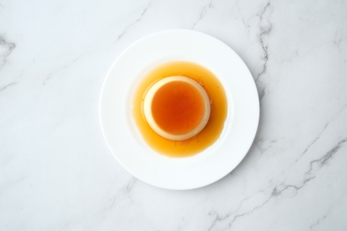 Caramel pudding plate on marble surface - Australian Stock Image
