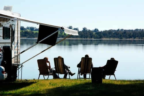 caravaners relax beside lake