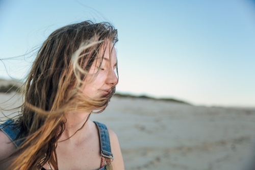 Carefree teenage girl on the beach with messy hair blowing in the wind - Australian Stock Image
