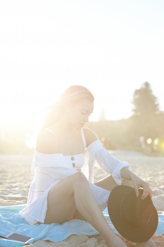 Carefree young blonde-haired woman at beach with black hat - Australian Stock Image