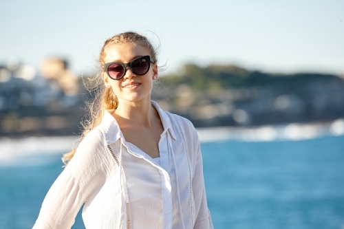 Carefree young blonde-haired woman at beach wearing sunglasses
