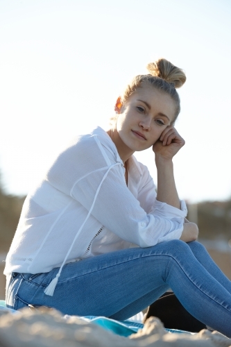 Carefree young blonde-haired woman at beach with hair in bun - Australian Stock Image