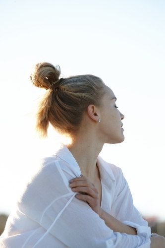 Carefree young blonde-haired woman at beach with hair in bun