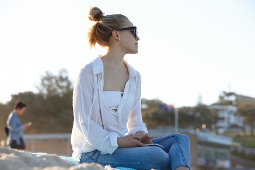 Carefree young blonde-haired woman at beach with hair in bun - Australian Stock Image