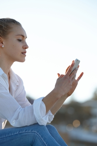 Carefree young blonde-haired woman checking mobile phone - Australian Stock Image
