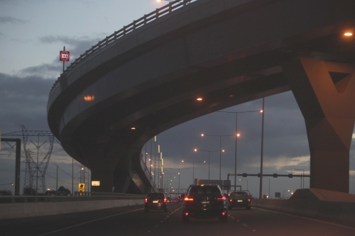 Cars passing under a bridge on Melbourne City roads in the evening - Australian Stock Image
