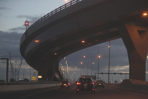 Cars passing under a bridge on Melbourne City roads in the evening