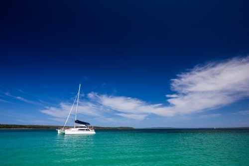Catamaran sailboat anchored on turquoise water